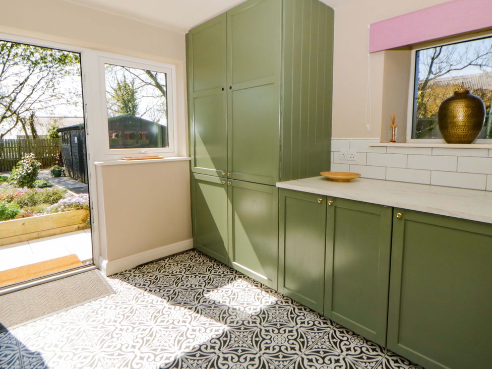 A kitchen with green cabinets and a window at La Bastille in Maenclochog