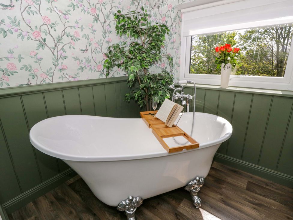 A bathtub with a book and glass at La Bastille in Maenclochog