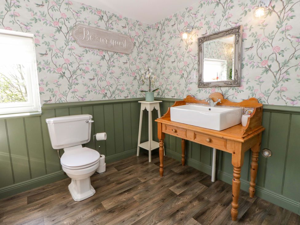 A bathroom with a toilet and sink against floral wallpaper at La Bastille in Maenclochog