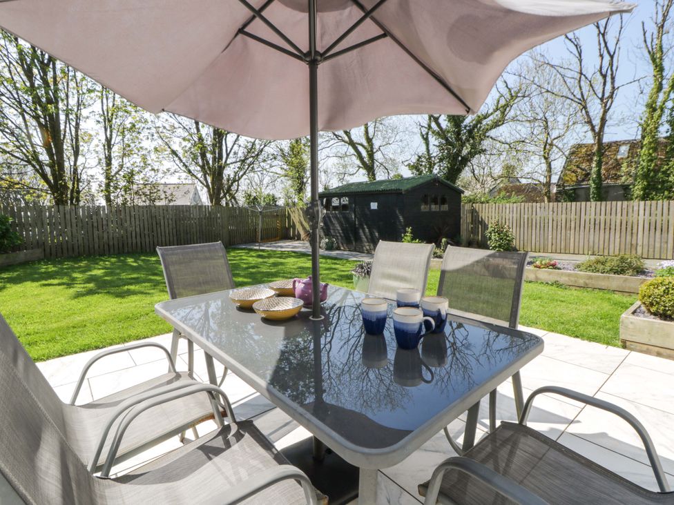 A garden with a table and chairs under an umbrella at La Bastille Maenclochog
