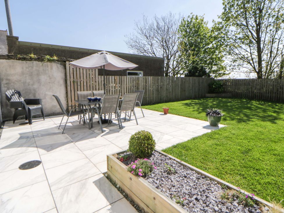 A garden with a table and chairs under an umbrella at La Bastille in Maenclochog