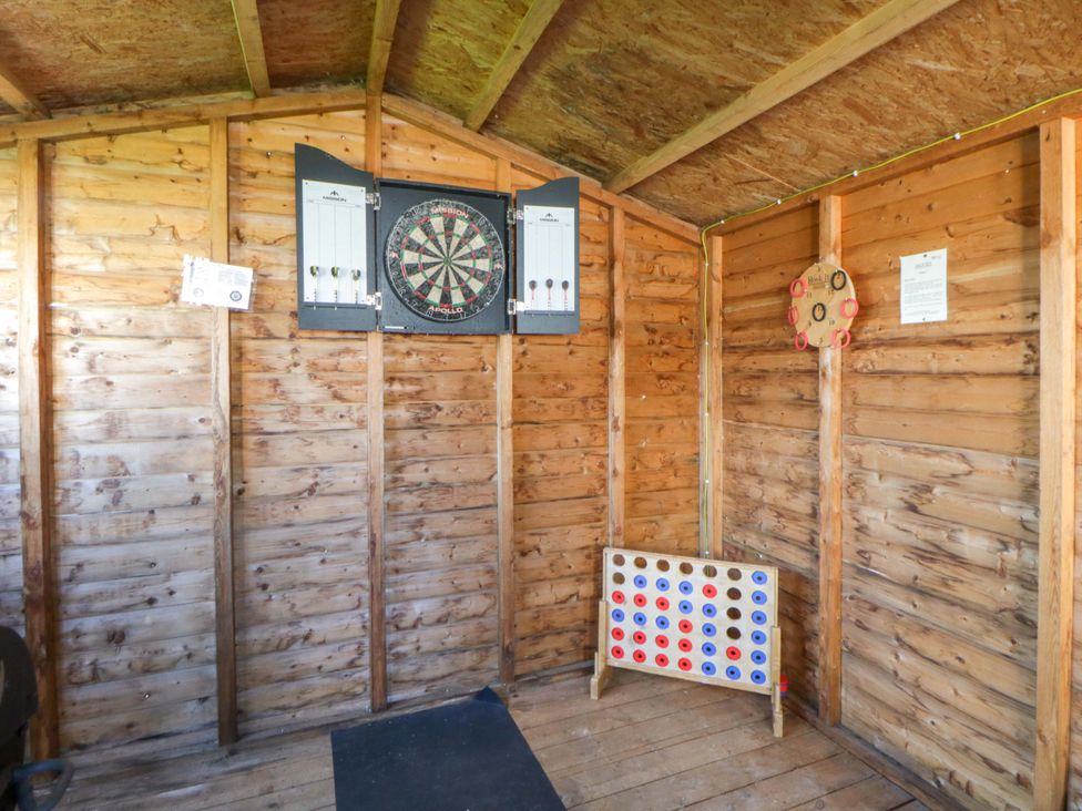 A games room with a dartboard and scoreboard at La Bastille in Maenclochog