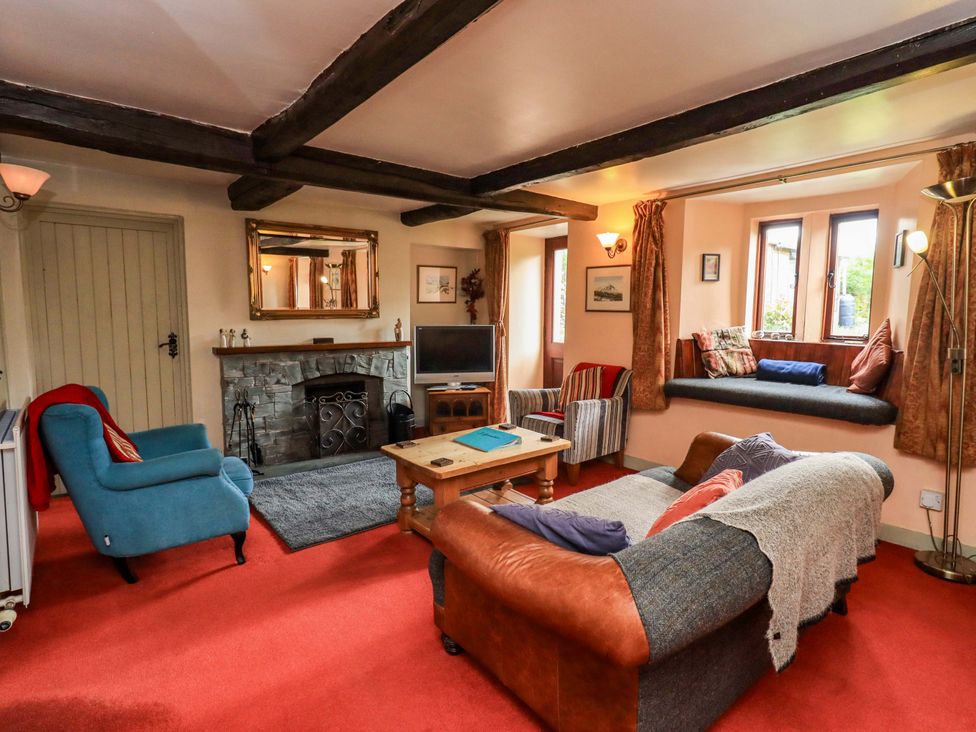 A living room with a sofa, coffee table, and television at Tethera Cottage in Bampton, Cumbria
