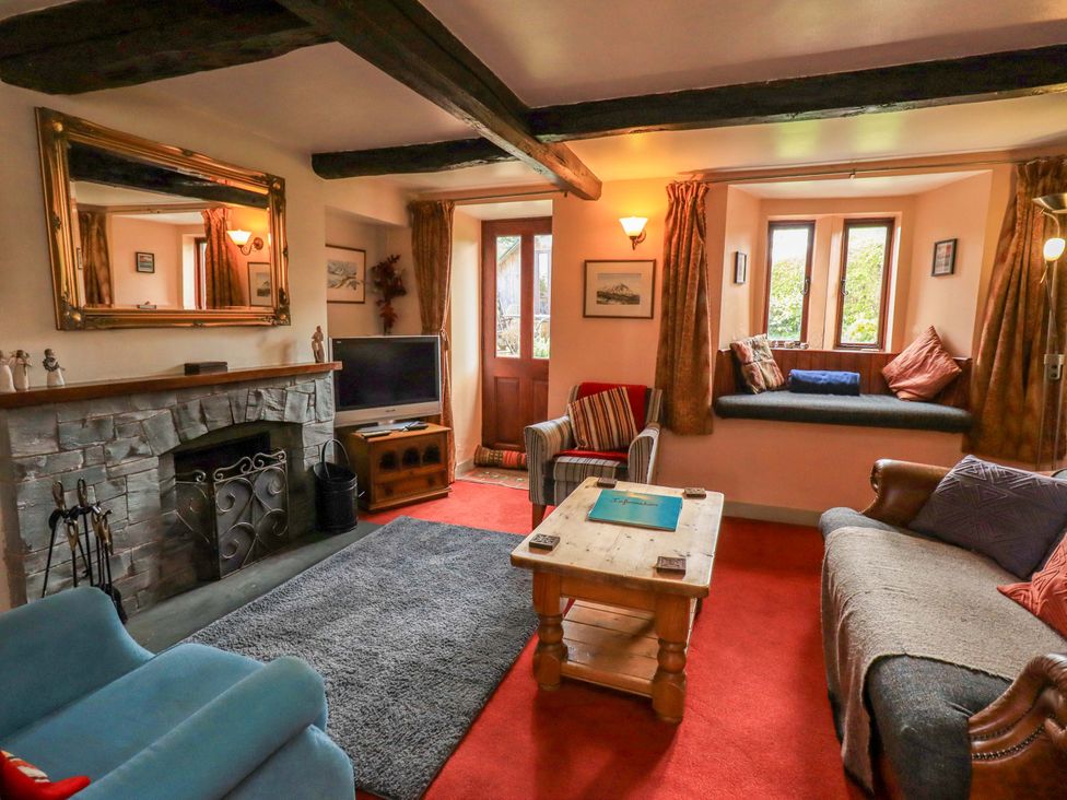 A living room with a fireplace and seating at Tethera Cottage in Bampton, Cumbria