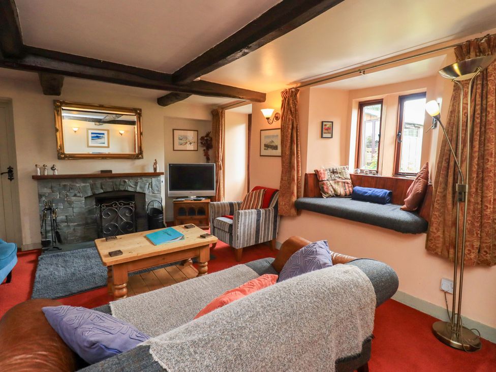 A living room with a fireplace and television at Tethera Cottage in Bampton, Cumbria