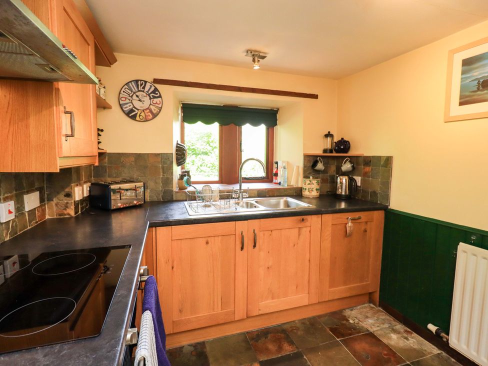A kitchen with a sink and oven at Tethera Cottage in Bampton, Cumbria