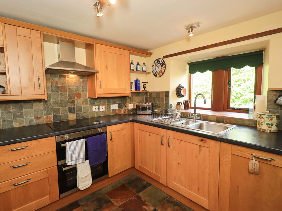 A kitchen with cabinets, sink, and appliances at Tethera Cottage in Bampton, Cumbria