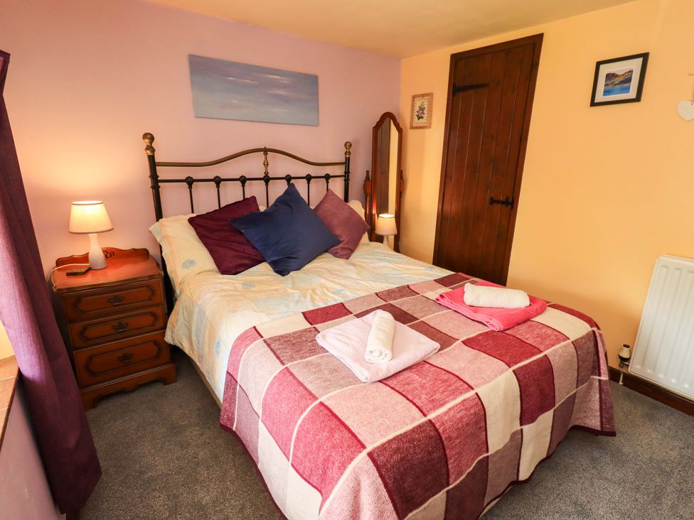 A bedroom with a bed and nightstand at Tethera Cottage in Bampton, Cumbria