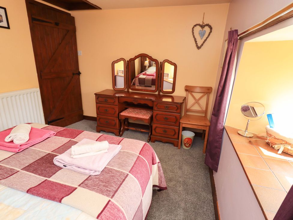 A bedroom with a bed and dressing table at Tethera Cottage in Bampton, Cumbria