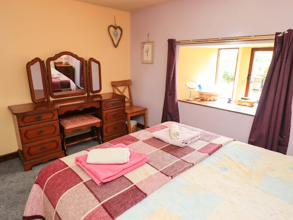A bedroom with a bed and vanity table at Tethera Cottage Bampton, Cumbria