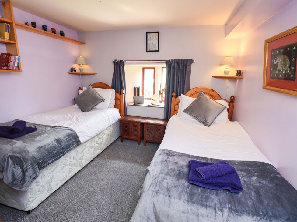 A bedroom with twin beds and a window at Tethera Cottage in Bampton, Cumbria