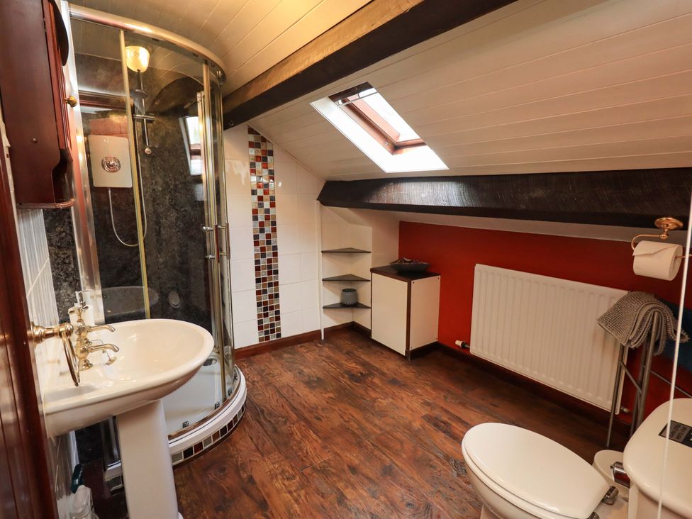 A bathroom with shower, sink and toilet at Tethera Cottage in Bampton, Cumbria