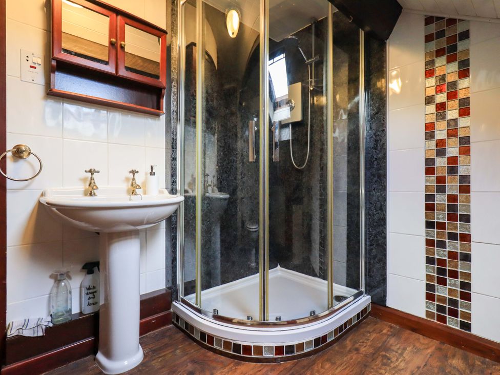 A bathroom with a shower and sink at Tethera Cottage in Bampton, Cumbria