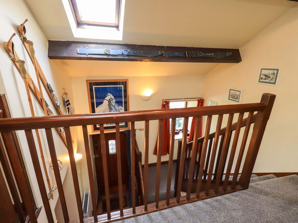 A staircase with skis and art on the wall at Tethera Cottage in Bampton, Cumbria