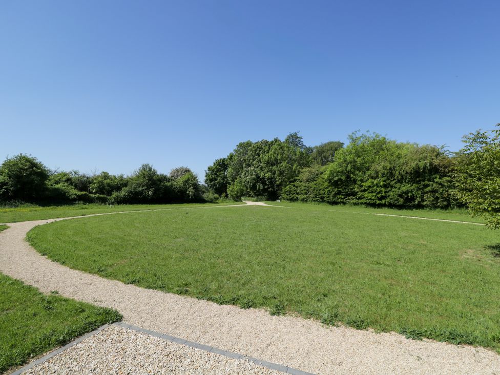 An outdoor grassy area with a gravel circular pathway and trees in the background at Hazel South Leigh near Witney