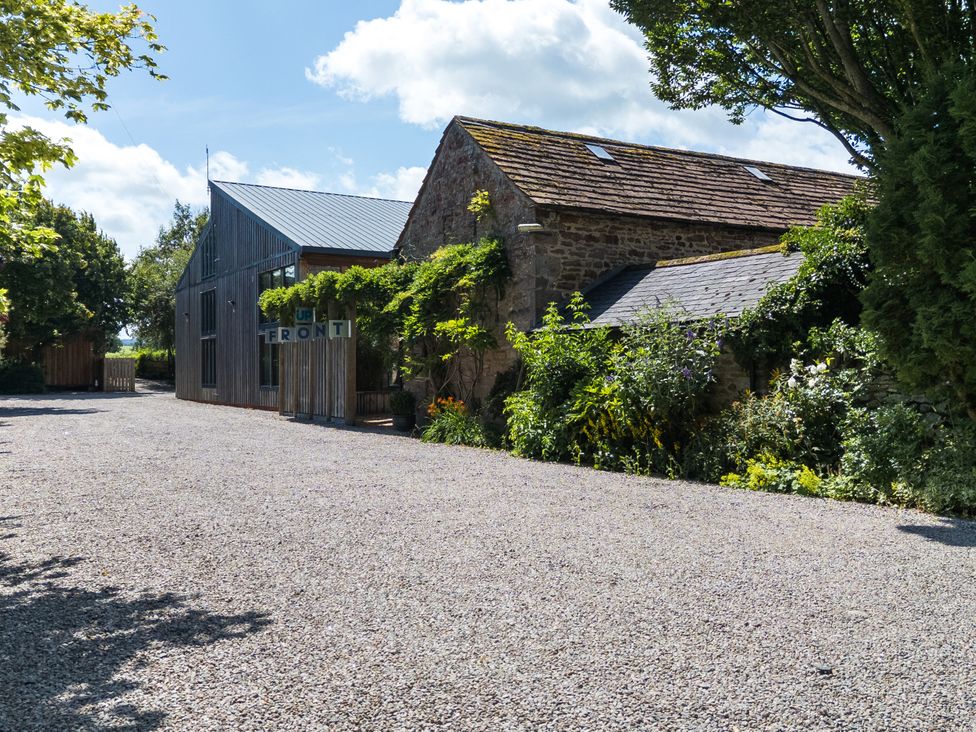 An outdoor area with gravel and buildings at Cedrus Lodge in Skelton near Penrith