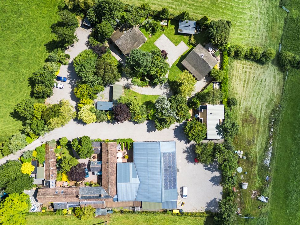 An aerial view of a property with houses and trees at Cedrus Lodge in Skelton near Penrith