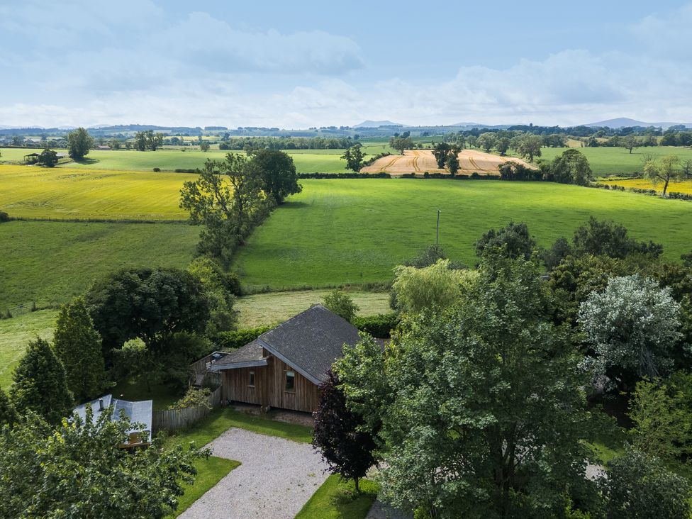 A view of fields and trees with a house in the foreground at Cedrus Lodge in Skelton near Penrith
