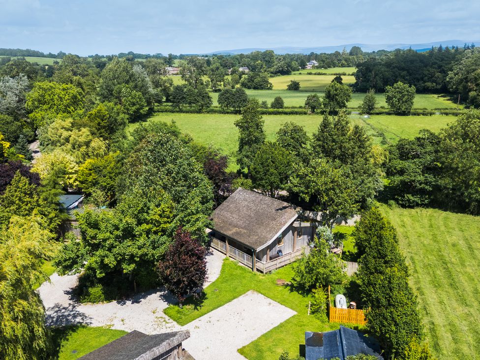 A view of a building surrounded by trees and grass at Larch Lodge in Skelton near Penrith