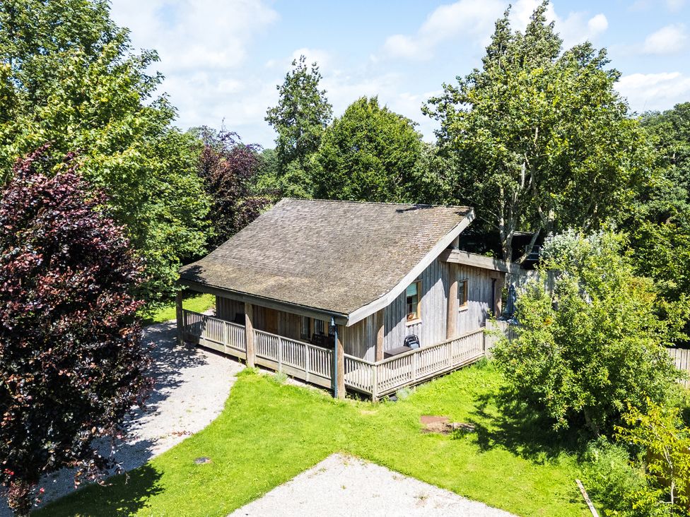 An outdoor view of a cabin surrounded by trees at Larch Lodge in Skelton near Penrith