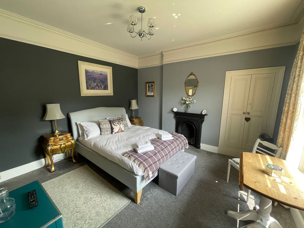 A bedroom with a bed, table, chairs, and decorative features at Deeley House in Darley Dale