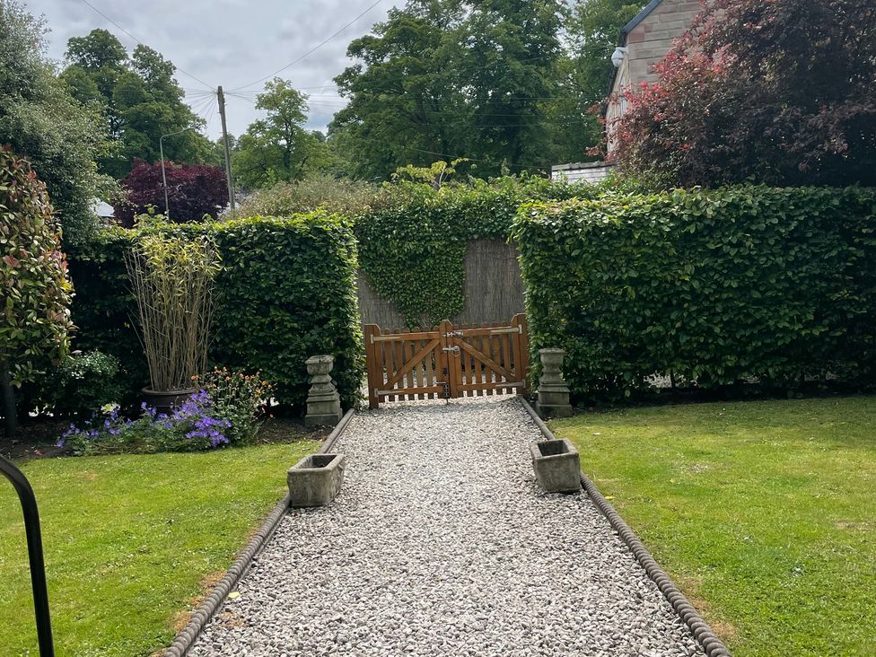 A garden with a gravel path and a wooden gate at Deeley House in Darley Dale