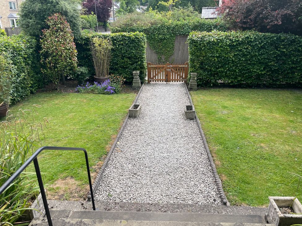 A garden with a gravel pathway and wooden gate at Deeley House Darley Dale