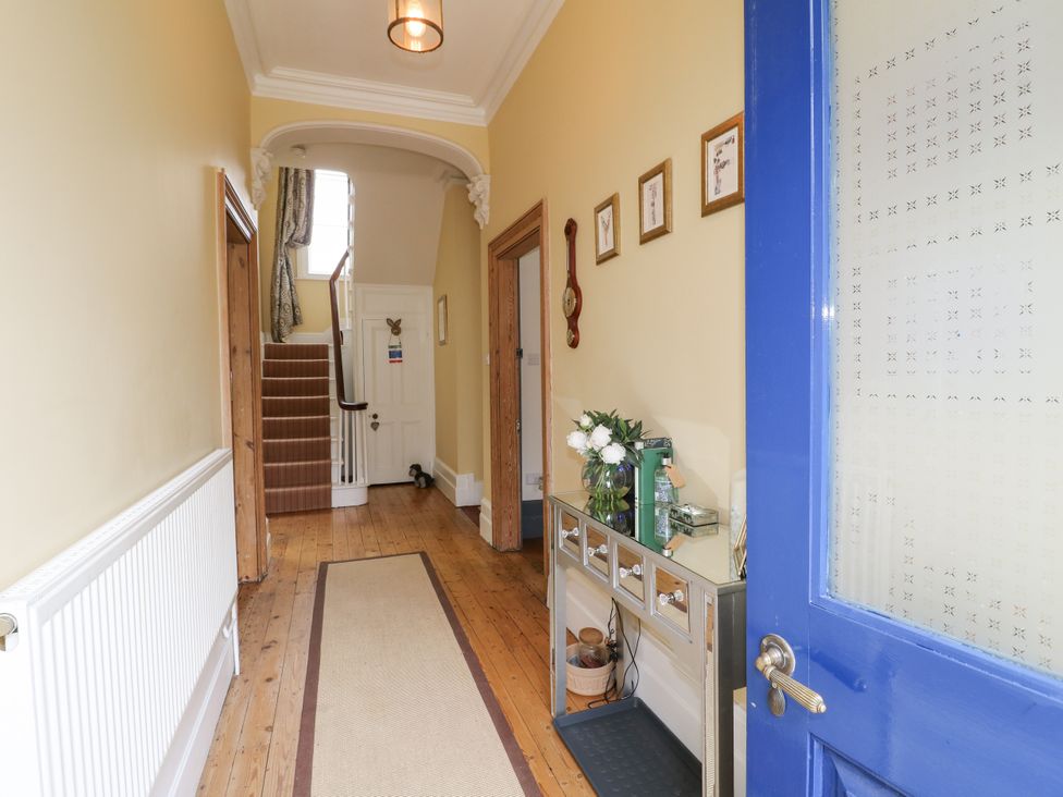 A hallway with a staircase and a table with a vase at Deeley House in Darley Dale