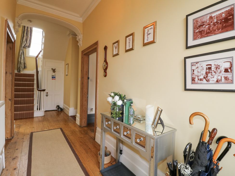A hallway with a staircase, table, and pictures at Deeley House in Darley Dale
