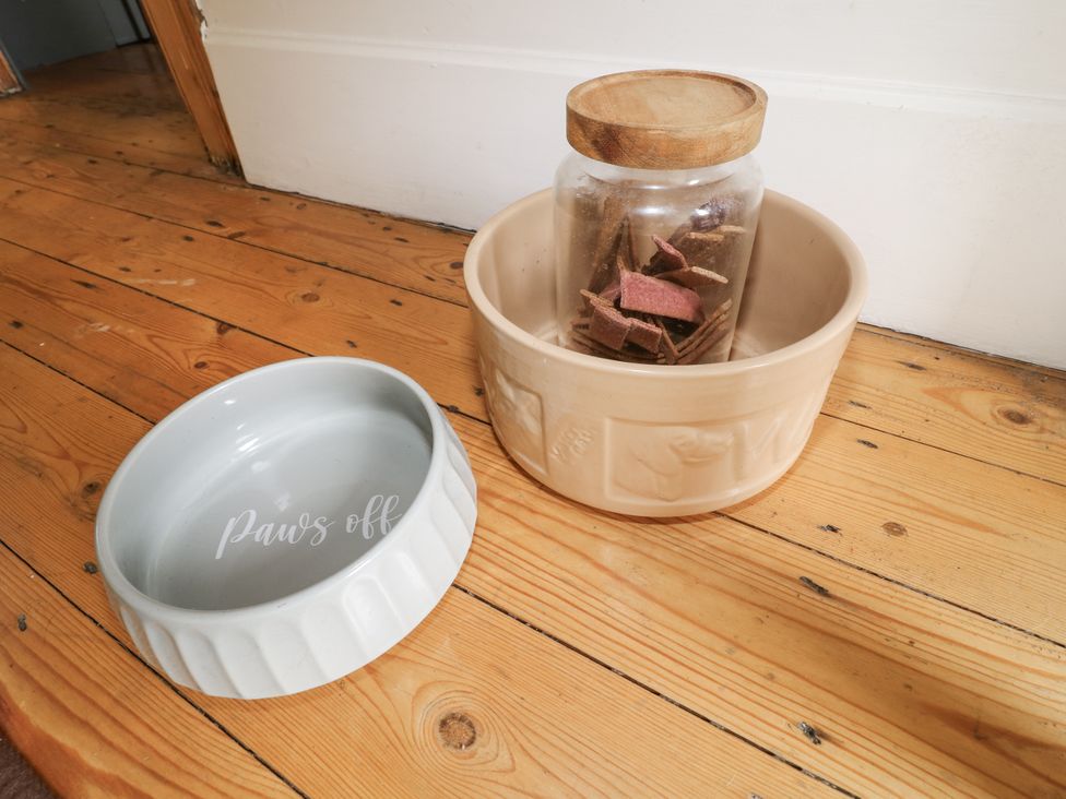 A dog bowl and treat jar on a wooden floor at Deeley House in Darley Dale