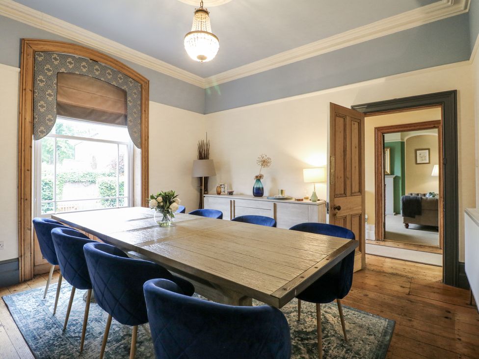 A dining room with a wooden table and blue chairs at Deeley House in Darley Dale