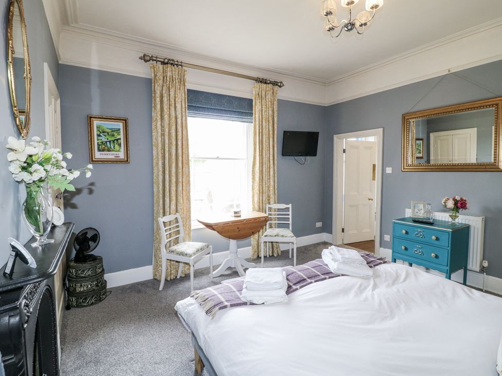 A bedroom with a bed, table, and chairs at Deeley House in Darley Dale