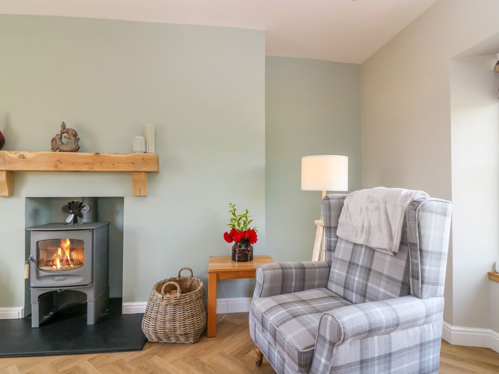 A living room with a fireplace and armchair at Ashlea Oxton near Lauder