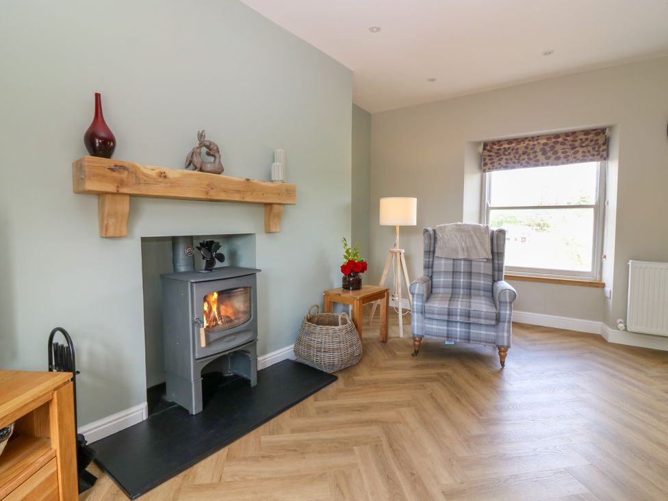 A living room with a fireplace and armchair at Ashlea in Oxton near Lauder