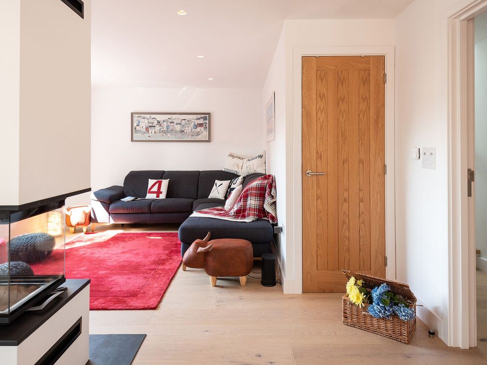 A living room with a sofa and a door at Pentire in St Minver