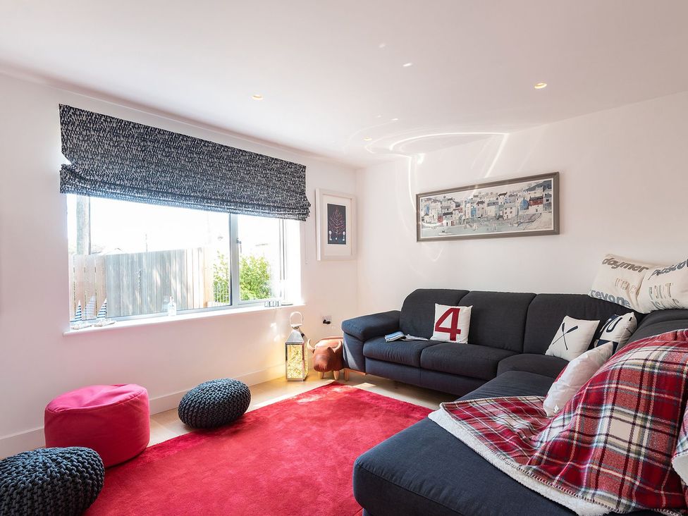 A living room with a sofa and cushions at Pentire, St Minver