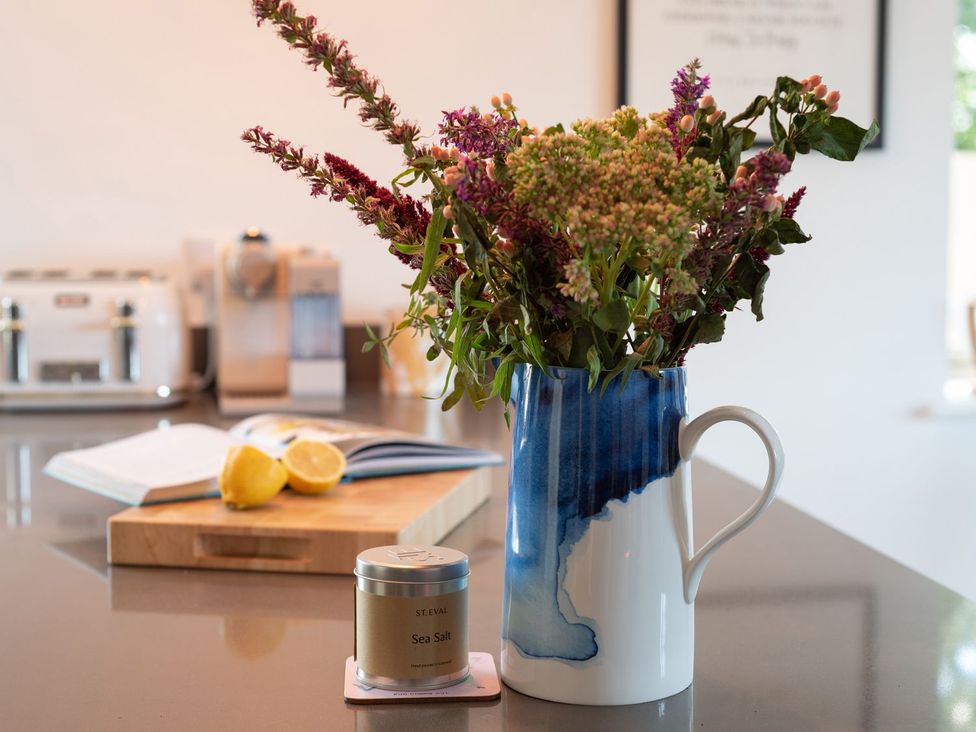 A kitchen with flowers in a pitcher and a cutting board with a lemon at Pentire St Minver