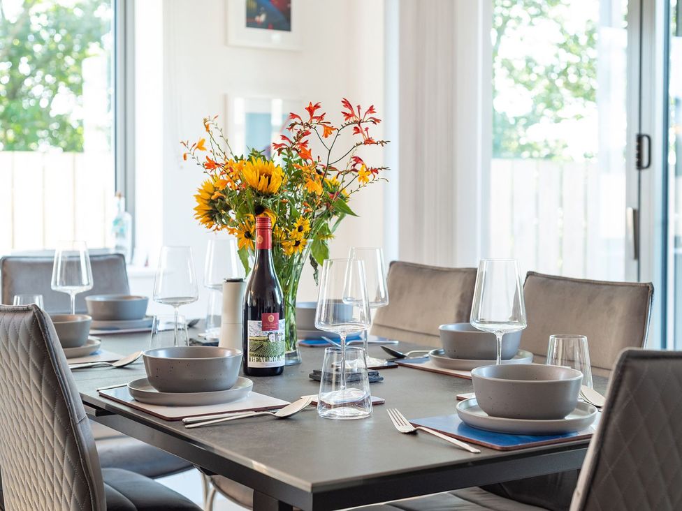 A dining room table set with dinnerware and a bouquet at Pentire in St Minver