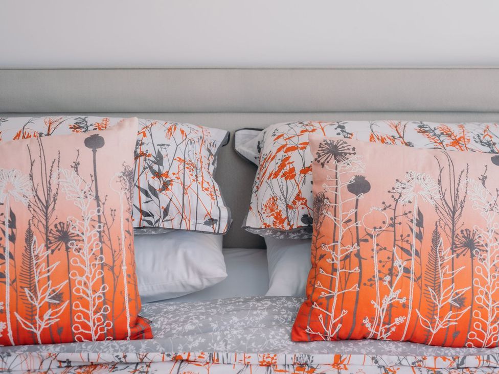 A bed with decorative pillows at Pentire in St Minver
