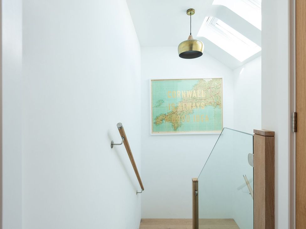 A staircase with a light fixture and a framed map at Pentire St Minver