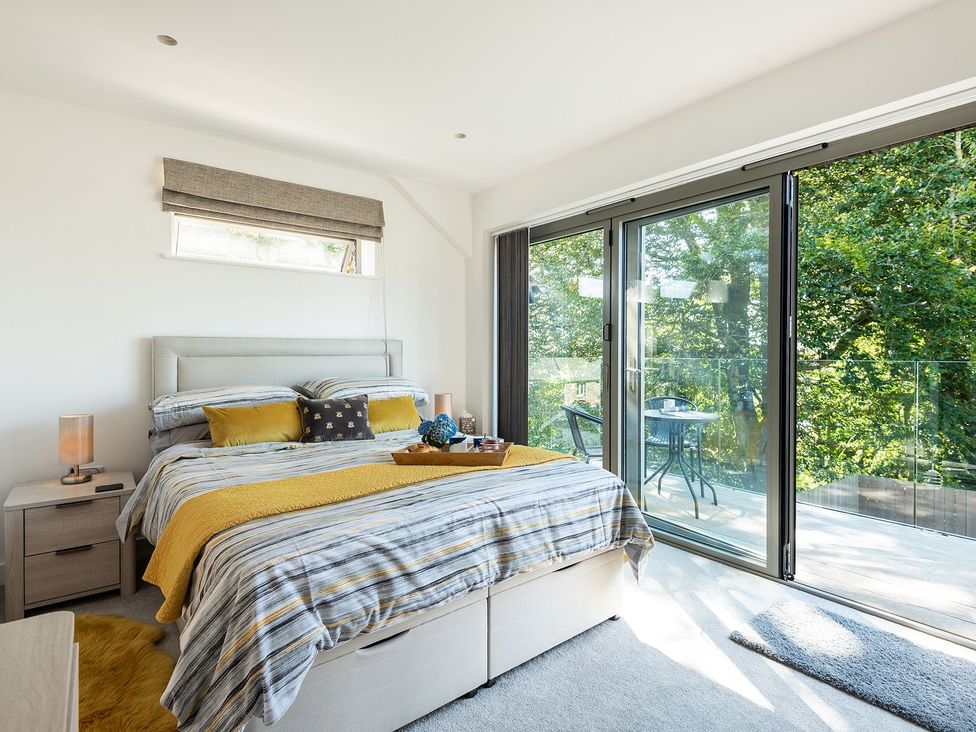 A bedroom with a bed and access to a balcony at Pentire in St Minver