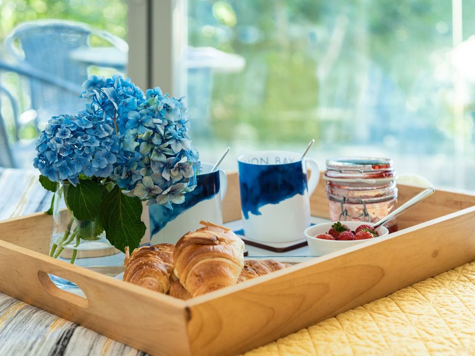 A tray with croissants, flowers, mugs, jam, and strawberries at Pentire St Minver