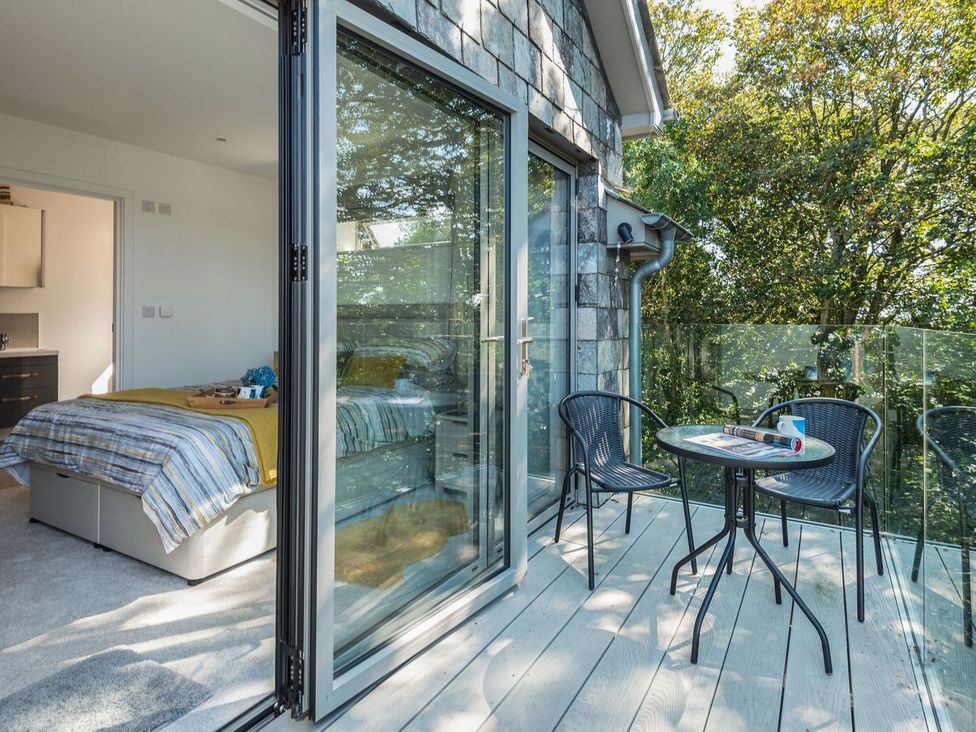 A bedroom with a sliding door and table on a balcony at Pentire in St Minver
