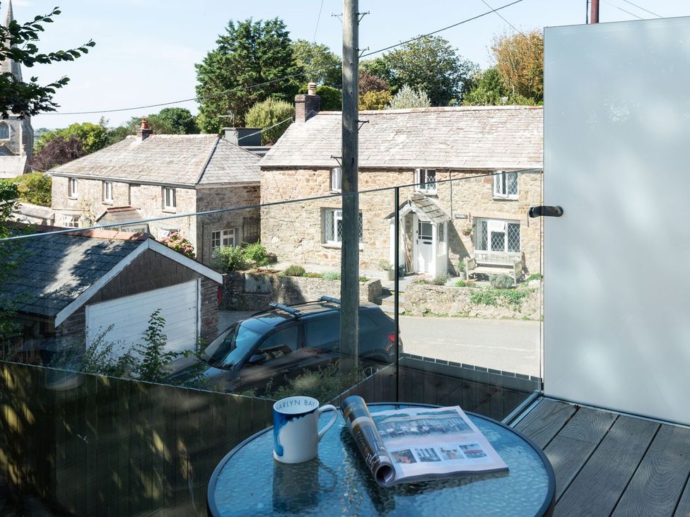 An outdoor area with a table, mug and magazine at Pentire in St Minver