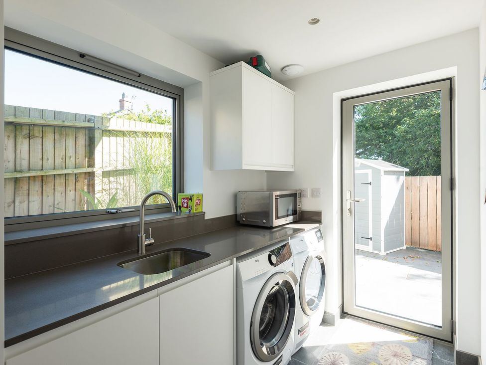 A laundry room with washing machine and sink at Pentire in St Minver