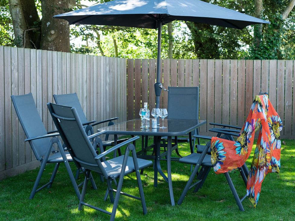 A garden with a table and chairs under an umbrella at Pentire St Minver