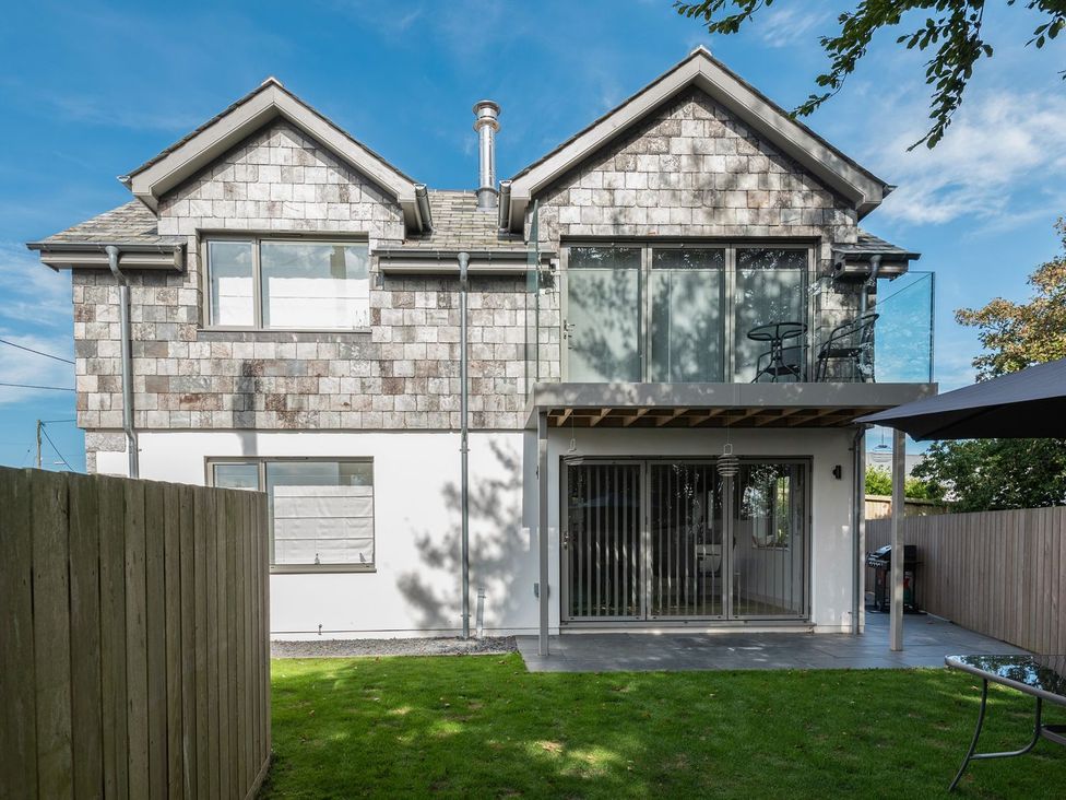 A house with a balcony and sliding door leading to the garden at Pentire in St Minver