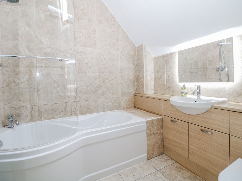 A bathroom with a bathtub, shower, and sink at 6 Fidlers Close in Bamford