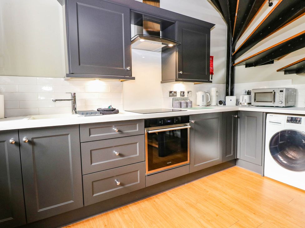 A kitchen with cabinets, oven, stove, sink, kettle, microwave, and washing machine at Horseshoe Stable Mattishall