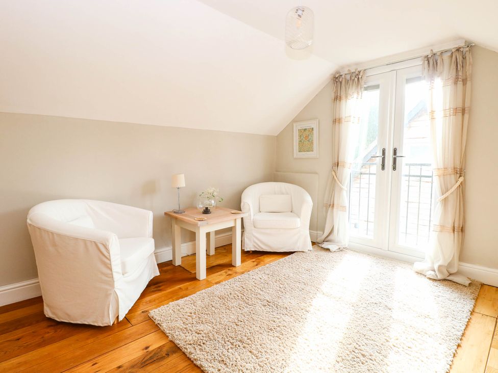 A snug room with two armchairs and a table at Horseshoe Stable in Mattishall